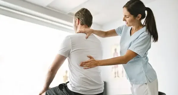 Provider guiding a patient through therapeutic movement at Palm Wellness Center
